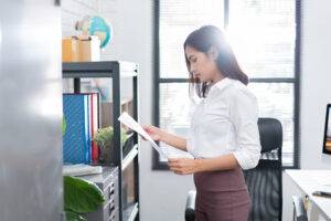 Frau bei der Durchsicht von Dokumenten im Büro.