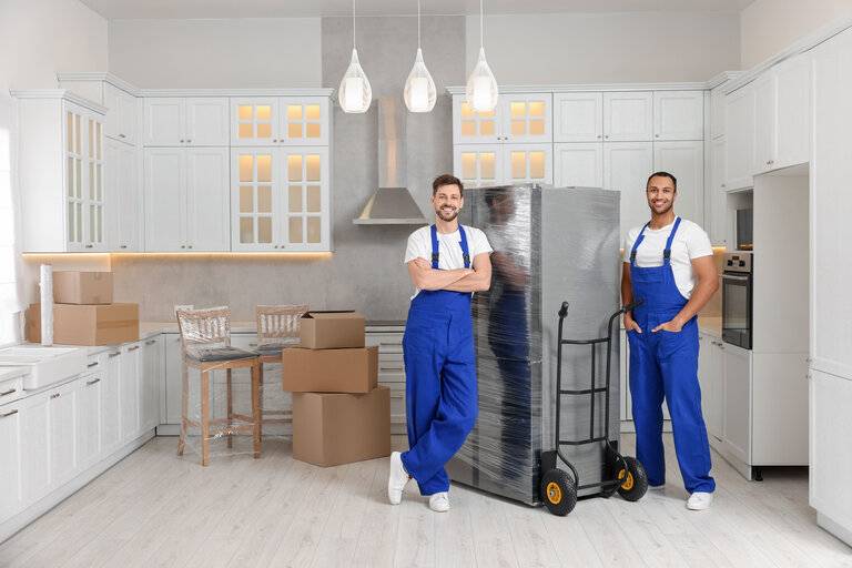 Männliche Umzugshelfer mit Kühlschrank im neuen Haus
