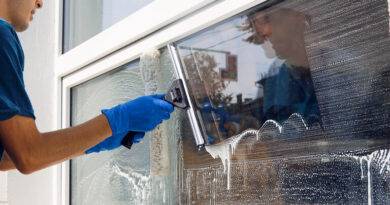 Ein Angestellter eines professionellen Reinigungsdienstes in einem Overall wäscht das Glas der Fenster an der Fassade des Gebäudes.
