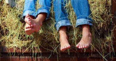 Beine in Jeans auf einem Heuhaufen