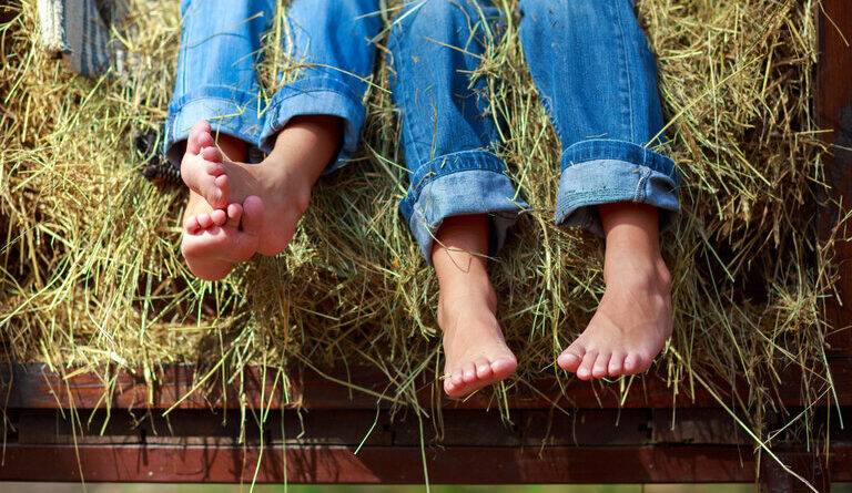 Beine in Jeans auf einem Heuhaufen