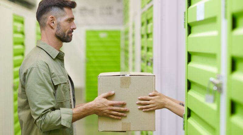 Ein Mann, der in einem Self-Storage-Lagerraum einen Karton übergibt