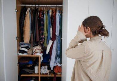 Frau steht ratlos vor überfülltem Kleiderschrank