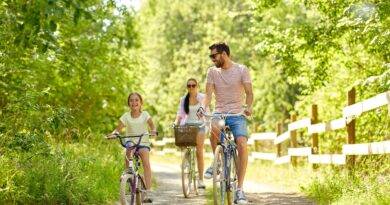 Familie, Freizeit und Menschenkonzept - glückliche Mutter, Vater und kleine Tochter fahren im Sommerpark Rad.