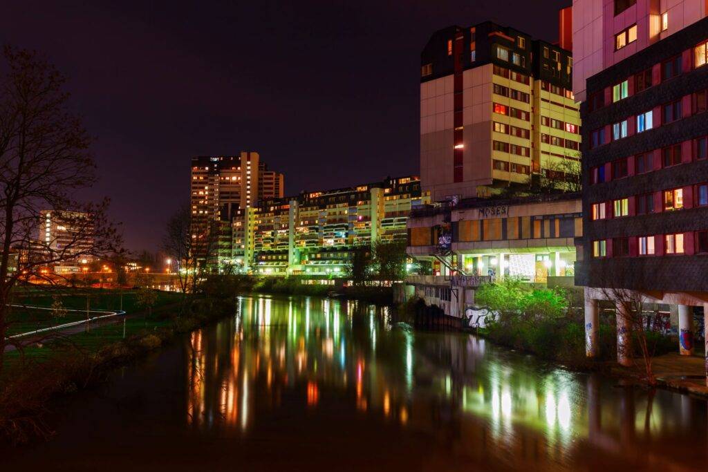 Ihme Zentrum Hannover bei Nacht mit Spiegelung im Wasser und beleuchteten Hochhaeusern