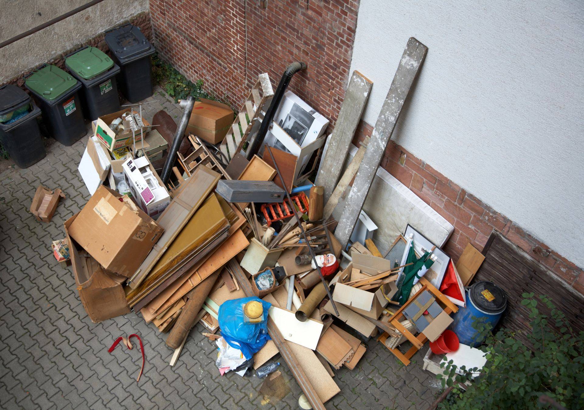 Sperrmuell im Hinterhof vor einer Wohnungsaufloesung – Beispiel fuer Entruempelung Oberhausen mit alten Moebeln, Kartons und Abfaellen

