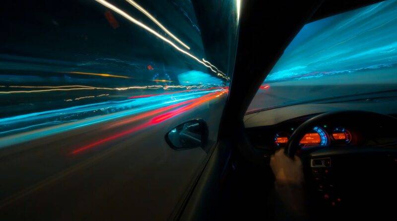 Blick aus dem Auto bei Nacht mit Lichtern und Geschwindigkeit, symbolisch für den abwechslungsreichen Alltag in Taxifahrer Jobs