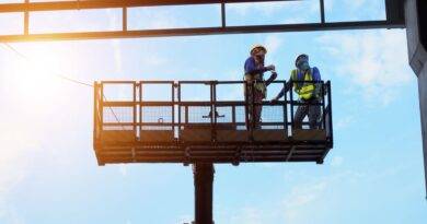 Zwei Bauarbeiter auf Arbeitsbühne im Stahlbau unter blauem Himmel in Oberhausen