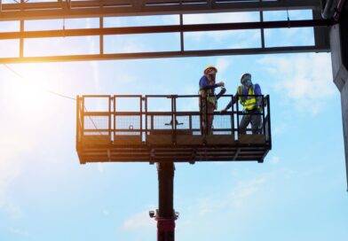 Zwei Bauarbeiter auf Arbeitsbühne im Stahlbau unter blauem Himmel in Oberhausen