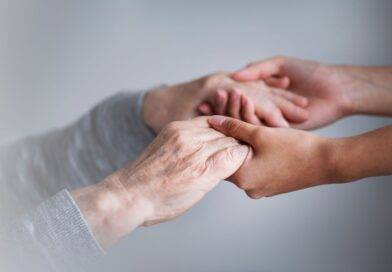 Zwei Personen halten sich die Hände – symbolisiert Nähe, Vertrauen und Fürsorge in der Pflege