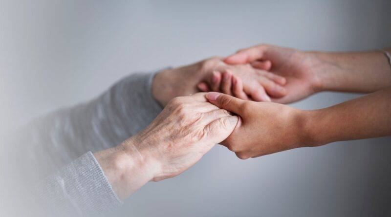 Zwei Personen halten sich die Hände – symbolisiert Nähe, Vertrauen und Fürsorge in der Pflege